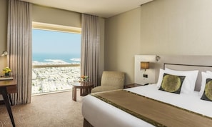 A hotel room with a bed, a desk, a chair, a nightstand, and a view of the cityscape. - The Tower Plaza Hotel Dubai (Dubai)