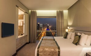 A hotel room with a bed, a TV, a window with a city view, and a bathroom with a shower and toilet. - The Tower Plaza Hotel Dubai (Dubai)