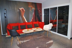 A modern living room with a red sofa, two chairs, a coffee table, and a large abstract painting on the wall. - Sure Hotel Spanga (Spånga)