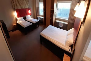 A hotel room with two beds, a desk, and a window with a view. - Sure Hotel Spanga (Spånga)