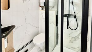 Ein modernes Badezimmer mit einer Duschkabine, einer Toilette und einem Waschtisch mit Spiegel.