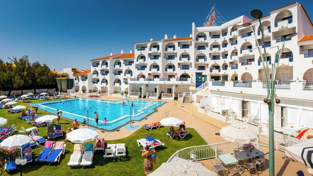 A hotel with a swimming pool, sun loungers, and outdoor seating areas. - Tropical Sol (Albufeira)