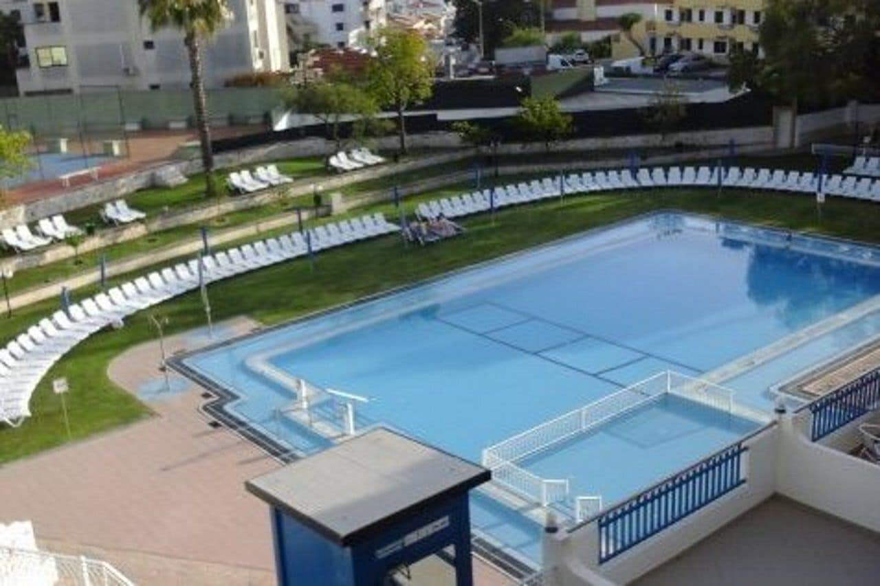 Une piscine avec des chaises longues et un petit pavillon.
