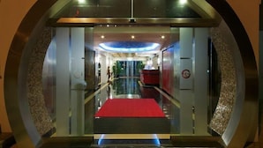 A hotel entrance with a glass facade, a red carpet, and a reception desk. - Tropical Sol (Albufeira)