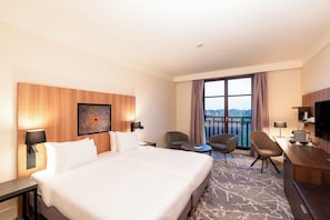 A hotel room with a large bed, two armchairs, a small table, a desk, and a TV. - Hotel Paris Marne-la-vallee (Magny-le-Hongre)