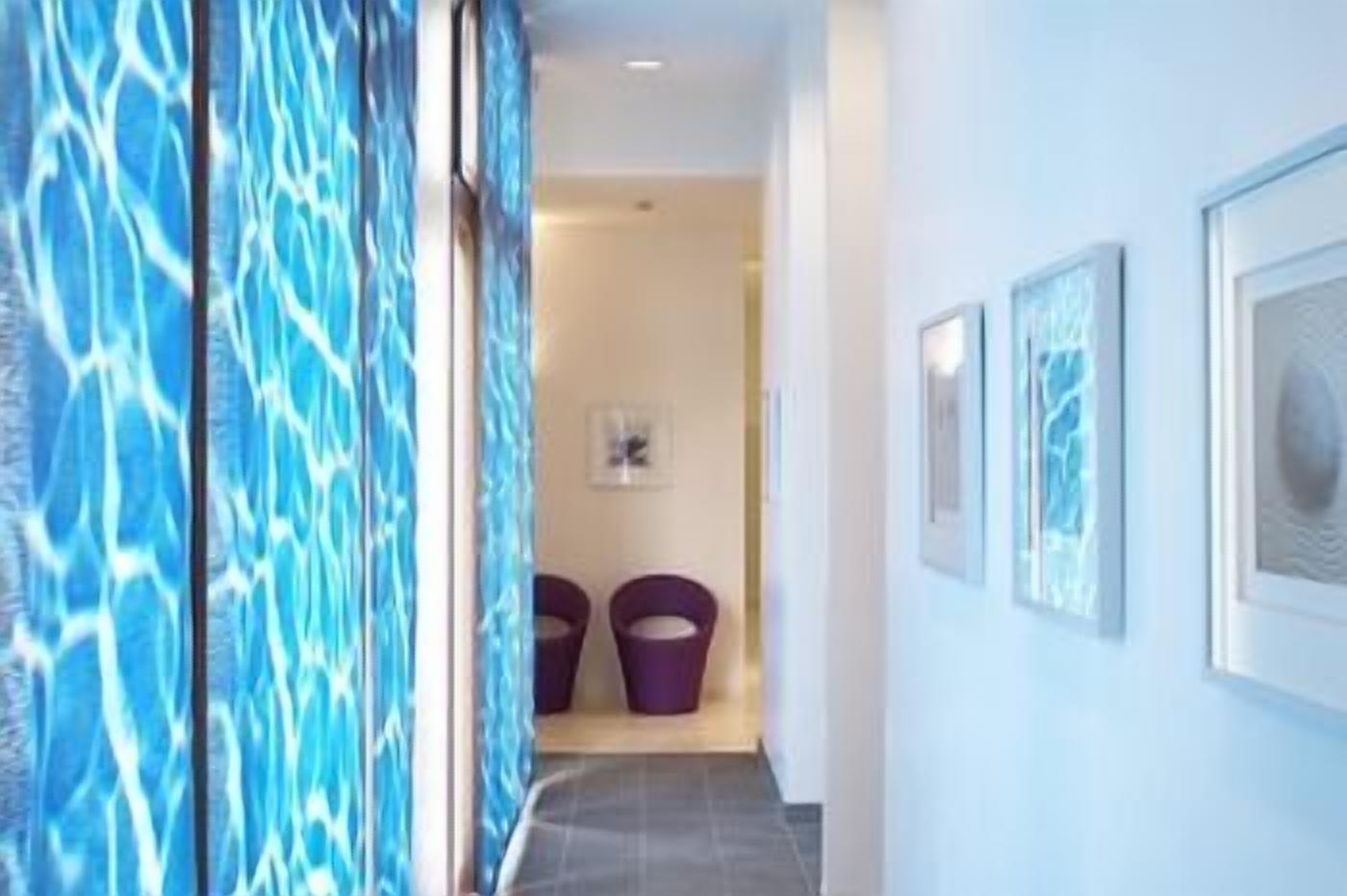 Un couloir avec un mur orné de motifs, une porte et un tableau encadré accroché au mur.