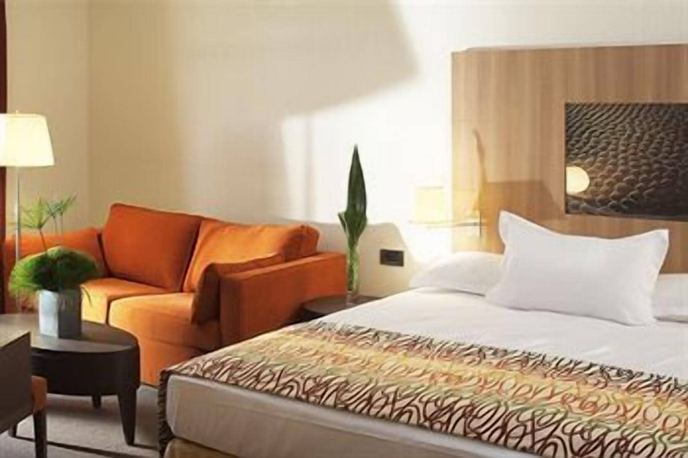 Une chambre d’hôtel avec un lit, un canapé, un bureau et une lampe.