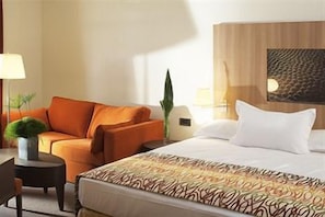 A hotel room with a bed, a sofa, a desk, and a lamp. - Crowne Plaza Paris Marne-la-vallée by IHG (Magny-le-Hongre)