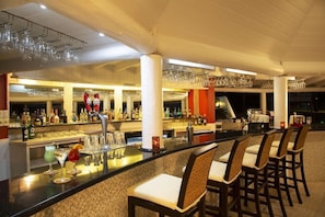 A bar area with a counter, bar stools, and a variety of bottles and glasses. - The Club Barbados Resort & Spa - Adults Only (Holetown)