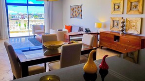 A hotel room with a dining area, a sofa, a desk, and a view of the city. - TAN Resorts Marina Cap Cana (Punta Cana)