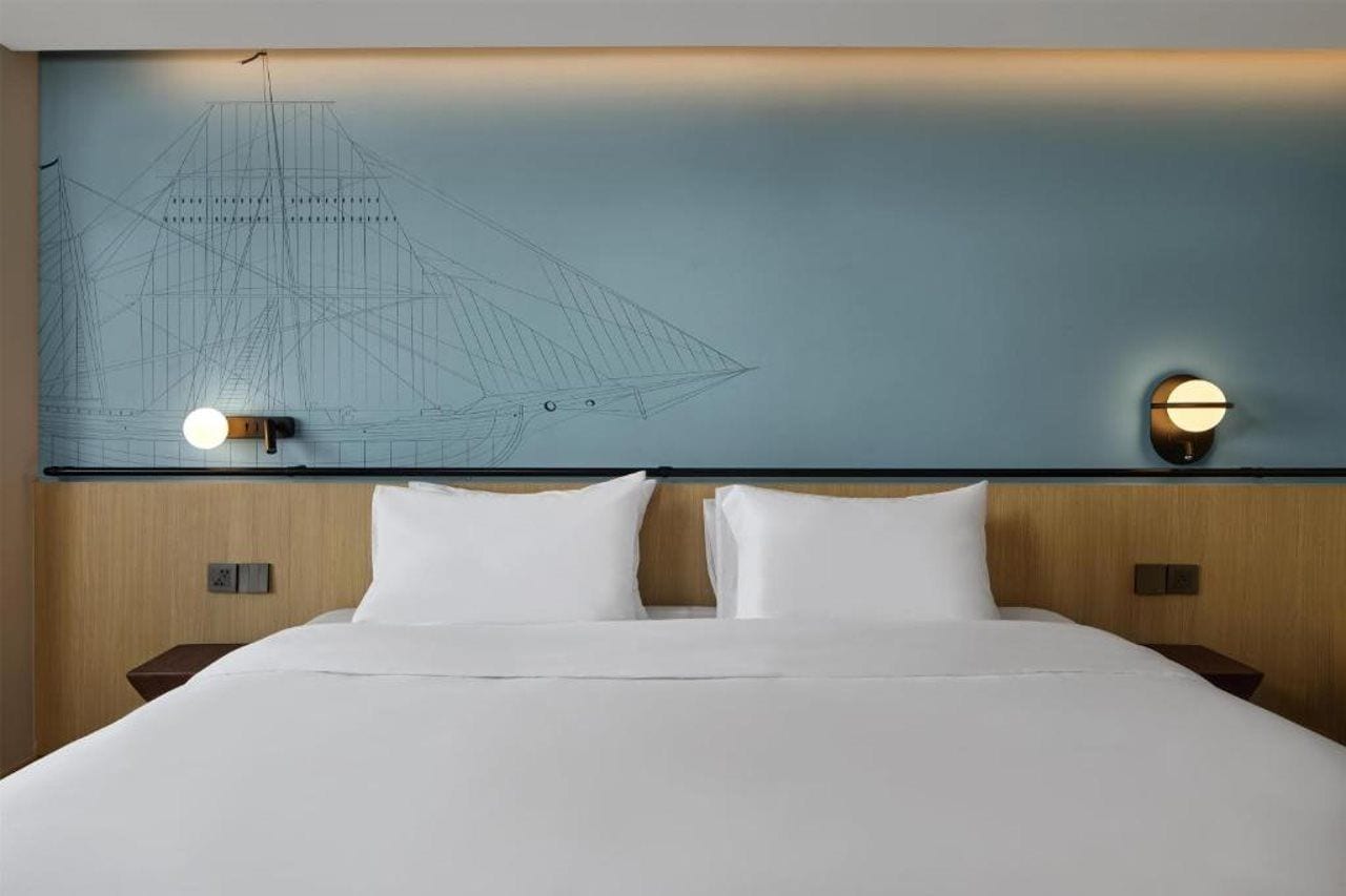 Een hotelkamer met een groot bed, twee nachtkastjes en een muur met een constructieplan ontwerp.