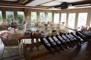 A dining area with wicker furniture and a row of wine bottles. - Best Western Matter Tiwanon Hotel (Pak Kret)