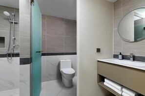 Une salle de bain moderne dotée d’une douche à parois de verre, de toilettes et d’un meuble-lavabo avec un miroir.