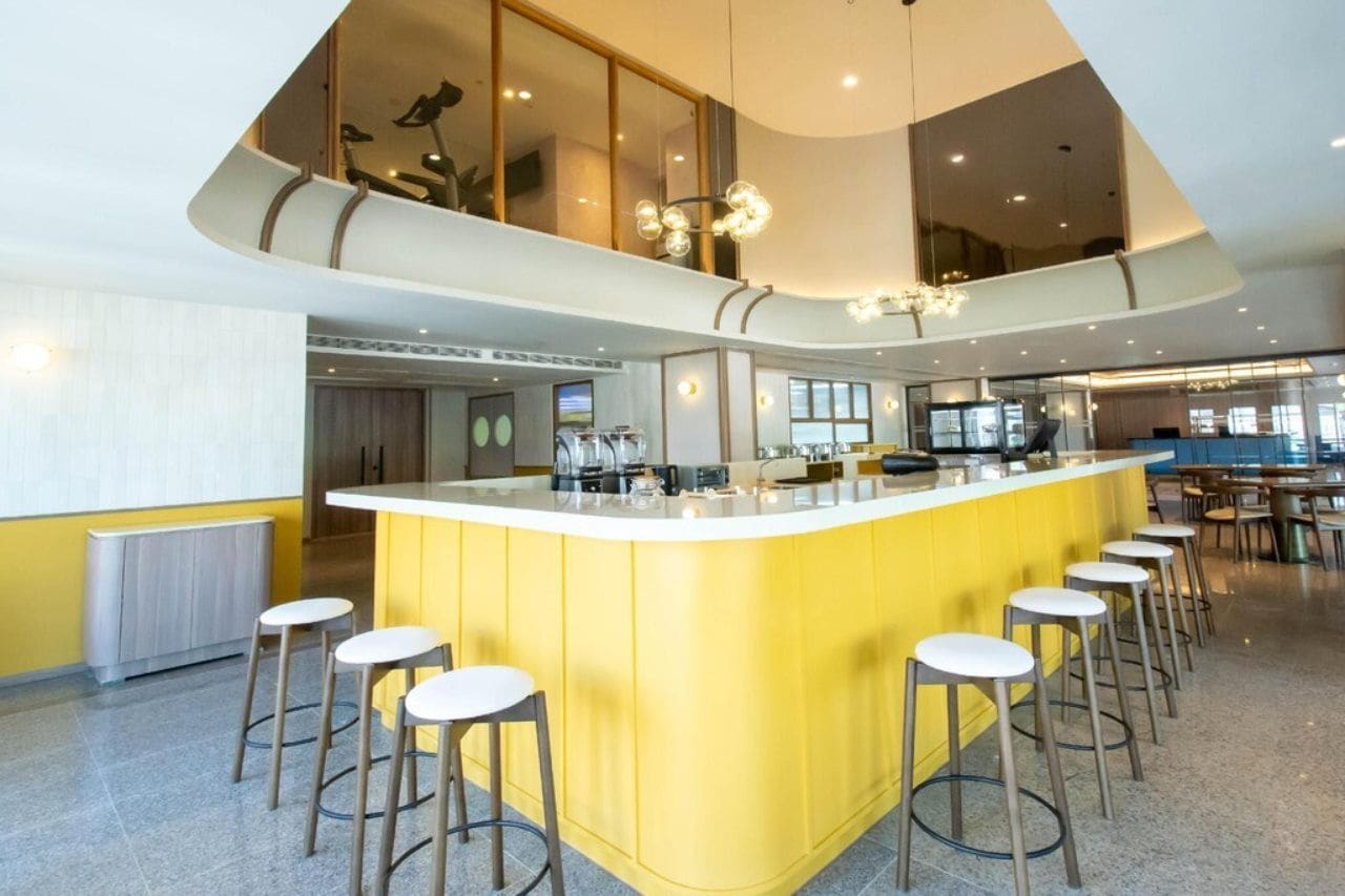 A modern kitchen with a central island, bar stools, and a high ceiling with a unique light fixture.