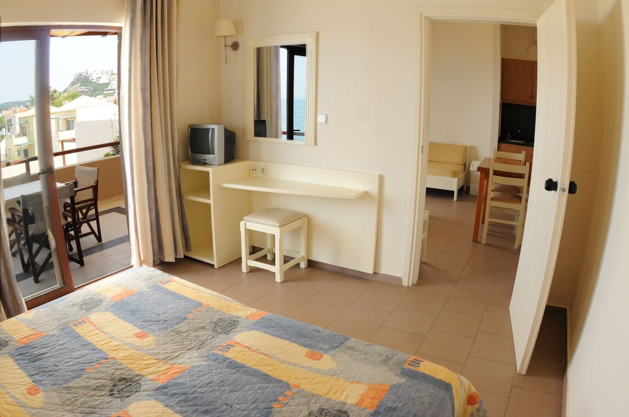 A hotel room with a bed, a desk, a television, a chair, and a view of the outside.