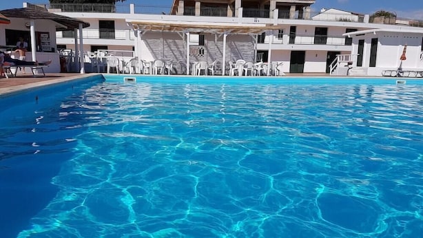 Ein Swimmingpool mit klarem, blauem Wasser, umgeben von weißen Gebäuden mit Balkonen und Terrassen.