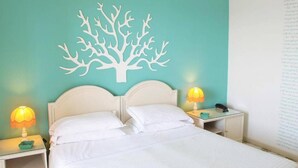 Ein Bett mit weißer Bettwäsche, zwei Nachttischlampen und einer an der Wand befestigten Baumdekoration.