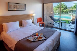Une chambre d’hôtel avec un lit, un plateau de petit-déjeuner, une chaise et une vue sur une piscine.