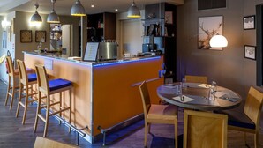 A bar area with stools, a round table, and pendant lighting. - Noemys Toulon La Valette (La Valette-du-Var)