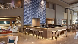 Un bar moderno con pared decorada, distintas opciones de asiento y techo alto.