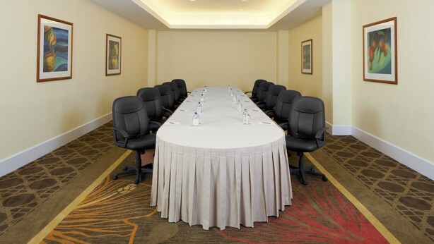 Una sala de conferencias con una larga mesa, sillas y cuadros en las paredes.