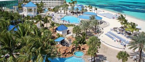 A resort with a large pool, beach area, and a hotel building.
