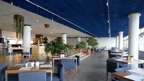 A spacious indoor area with multiple seating arrangements, including tables and chairs, and several potted plants. - Cavaliere Sur Plage (Le Lavandou)