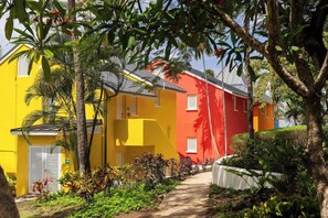 A residential area with colorful buildings, a pathway, and tropical vegetation. - Crystal Cove by Elegant Hotels - All-inclusive (Derricks)