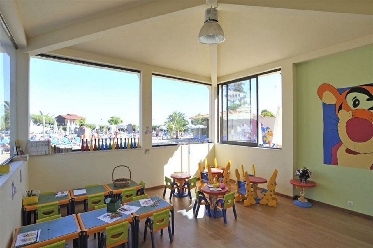 A classroom with large windows, colorful furniture, and a mural on the wall.
