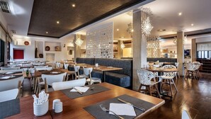 Un restaurante moderno con mesas de madera, sillas blancas y una zona central con un banco acolchado.
