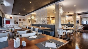 Un restaurant moderne avec des tables en bois, des chaises blanches et un espace central avec un banc rembourré.