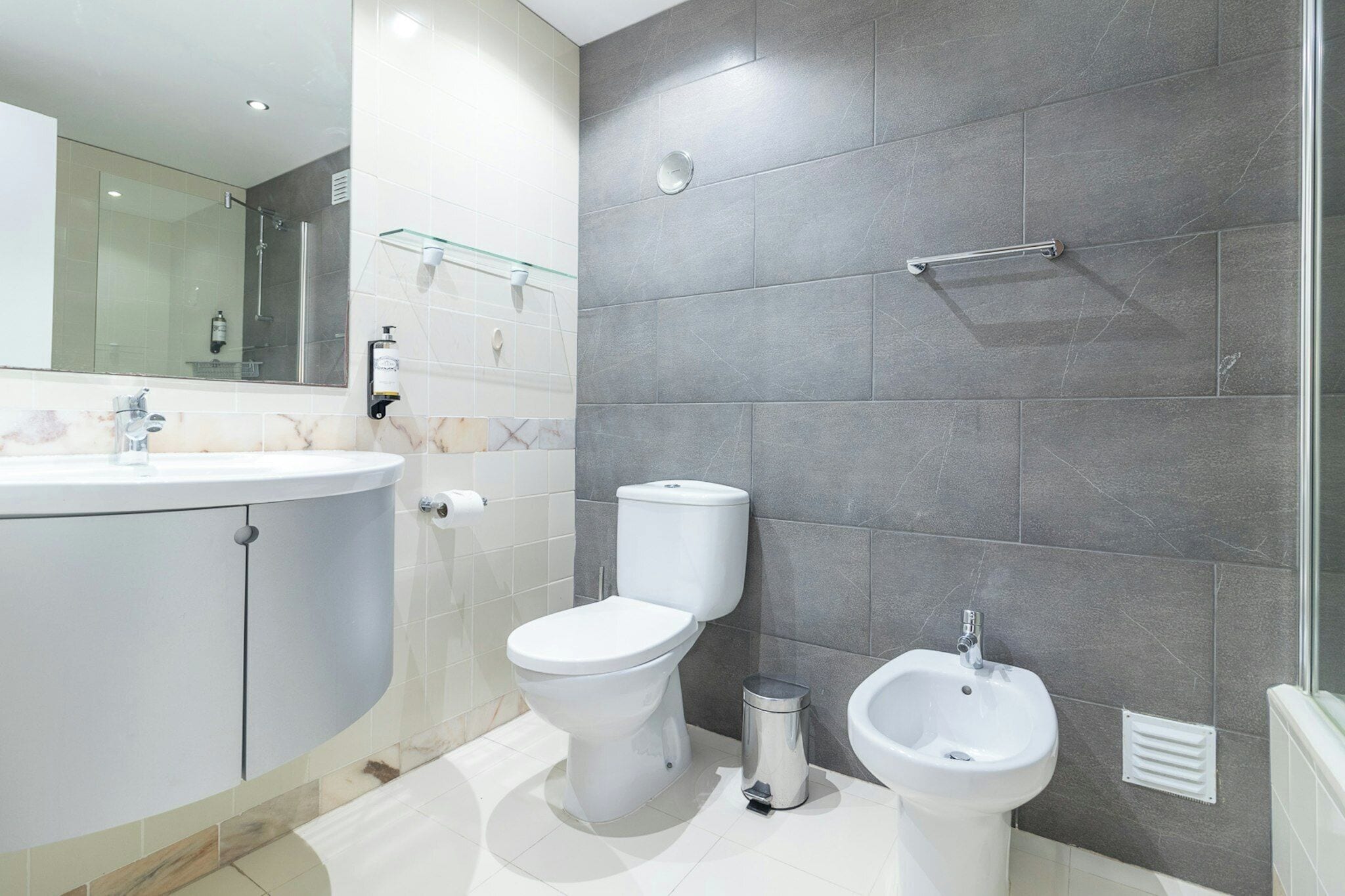 Un baño moderno con inodoro, bidé y cabina de ducha de vidrio.