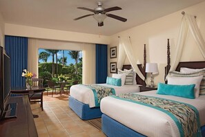 A hotel room with two beds, a ceiling fan, a desk with a chair, and a view of the outdoors. - Dreams Palm Beach (Punta Cana)