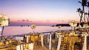 An outdoor dining setup with tables and chairs, a view of the ocean, and palm trees. - Jewel Palm Beach Resort Spa (Punta Cana)