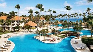 A resort with a large swimming pool, palm trees, and beachfront villas. - Jewel Palm Beach Resort Spa (Punta Cana)