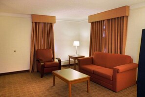 A hotel room with a sofa, armchair, and a small table. - Baymont by Wyndham San Antonio South Park (San Antonio)