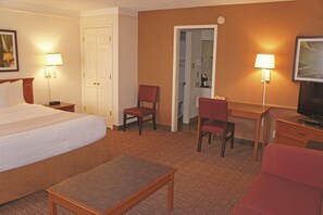 A hotel room with a bed, two chairs, a desk, a television, and two lamps. - Baymont by Wyndham San Antonio South Park (San Antonio)