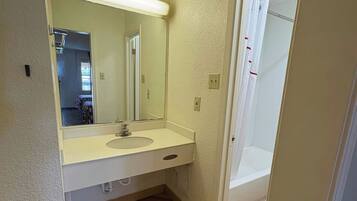 A bathroom with a sink, mirror, and shower.