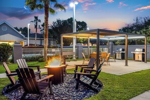 An outdoor patio area with a fire pit, seating, and a covered grill station. - Homewood Suites by Hilton Pensacola Arpt (Pensacola)