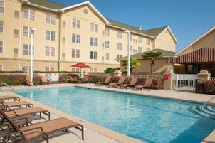 Un hôtel doté d’une piscine, de chaises longues et d’un espace abrité.