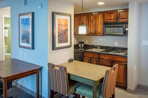 Una cocina con armarios de madera, un microondas y una zona de comedor con sillas a rayas.