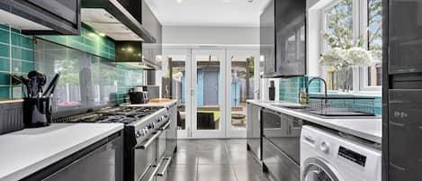 A modern kitchen with stainless steel appliances, a built-in oven, and a washing machine.