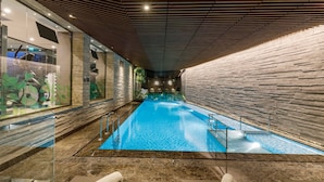 Una piscina interior con pared de piedra y techo de madera.