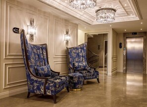 A hotel lobby with two blue patterned armchairs, a chandelier, and a marble floor. - Amiral Palace Boutique Hotel (Istanbul)