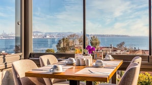 Una mesa de comedor con sillas, vistas a un paisaje urbano y una masa de agua.