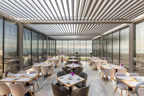 A modern restaurant with a glass ceiling, large windows, and a view of the cityscape. - Amiral Palace Boutique Hotel (Istanbul)