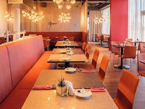 En restaurant med både båse og borde, varm belysning og moderne indretning.