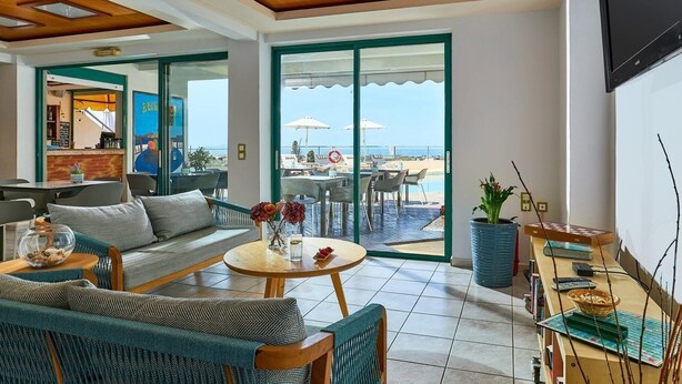 Una habitación de hotel moderna con sofá, mesa de comedor y vistas al área de la piscina.