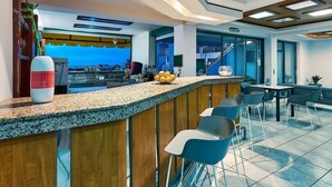 Zona de bar moderna con una barra, taburetes y vistas a la ciudad.