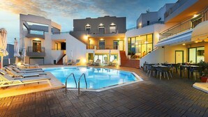 Un hotel moderno con piscina, mobiliario exterior y una escalera que conduce a los pisos superiores.